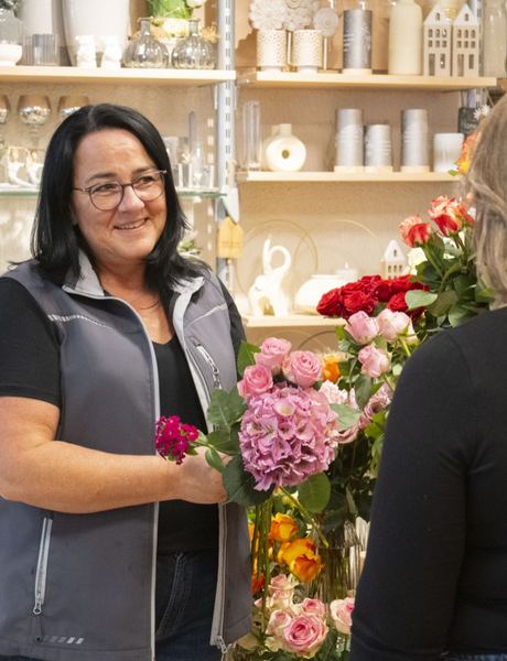 Übergabe eines Blumenstraußes an eine Kundin